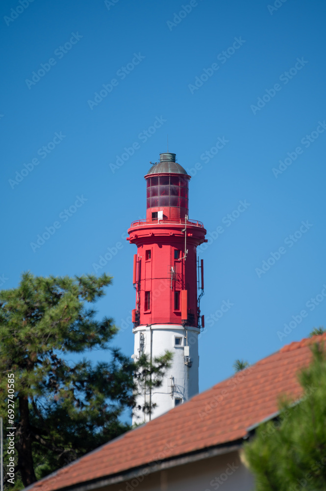 View on red lighthouse Le Phare du Cap Ferret, Arcachon Bay with many fisherman's boats and oysters farms near , Cap Ferret peninsula, France, southwest of Bordeaux, France's Atlantic coastline