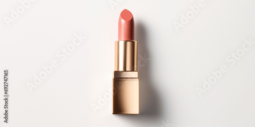 An peach fuzz color lipstick in a golden case on a white background. Make up a product show off. Copy space. photo