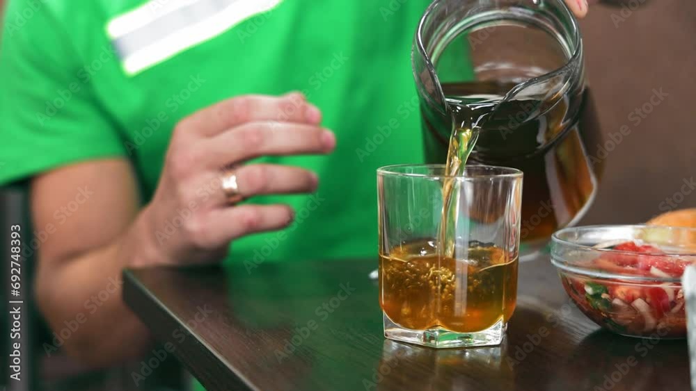 Pouring Tea into Glass at Cafe. Hand pouring dark tea into a clear glass Pouring Tea into Glass at Cafe. Hand pouring dark tea into a clear glass