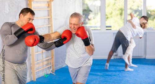 Two men in group boxing classes practicing sparring technique of blowing to head in gym © JackF