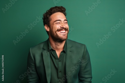 Portrait of a handsome young man laughing on a green background.