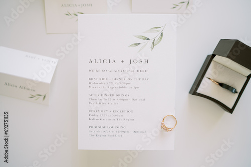 Engagement ring lies on a wedding invitation next to a box and name cards photo