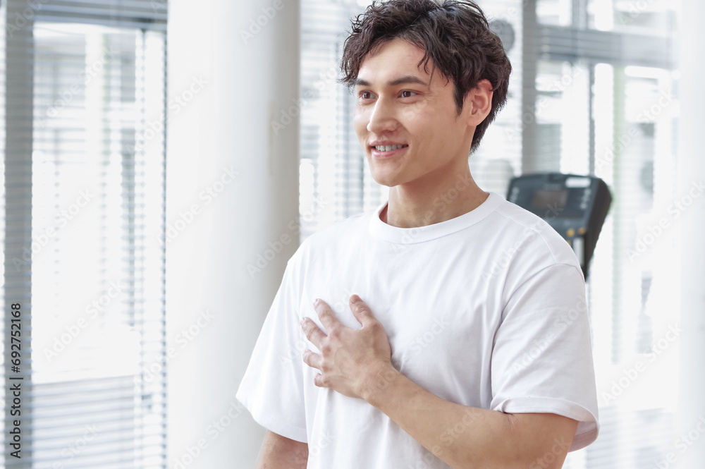 トレーニング施設で胸筋をさわっている男性 トレーニング施設で胸筋をさわっている男性