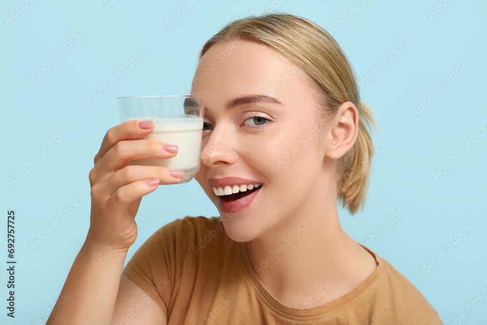 Pretty young woman with glass of milk on blue background Pretty young woman with glass of milk on blue background