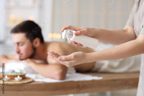 Massage therapist with cream in spa salon  closeup