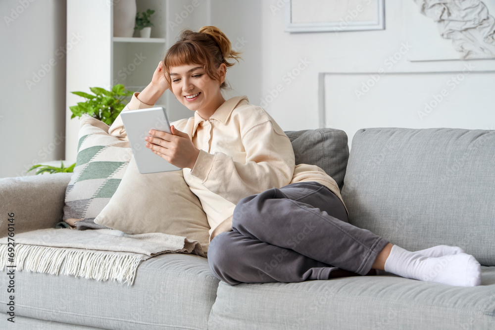 Young woman with tablet computer relaxing on sofa at home Young woman with tablet computer relaxing on sofa at home