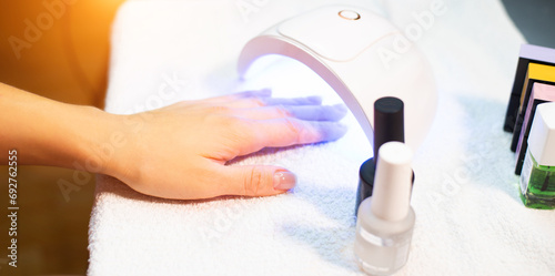 Female hand with transparent gel polish  base dry it under an ultraviolet lamp at home