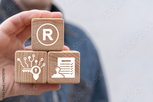 Man holding wooden blocks with icon sees sigr with letter: R. Registered trademark ( R ) copyright or patent concept. Trade mark protection. photo