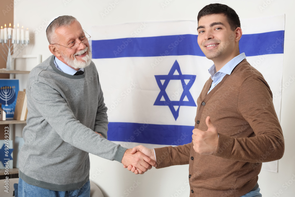 Young man with his father shaking hands at home on Hanukkah Young man with his father shaking hands at home on Hanukkah