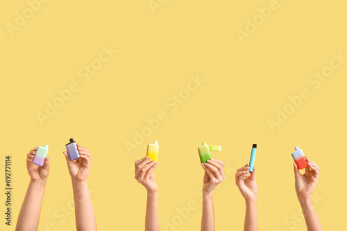 Female hands with different electronic cigarettes on color background photo