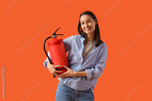 Young woman with fire extinguisher on orange background photo