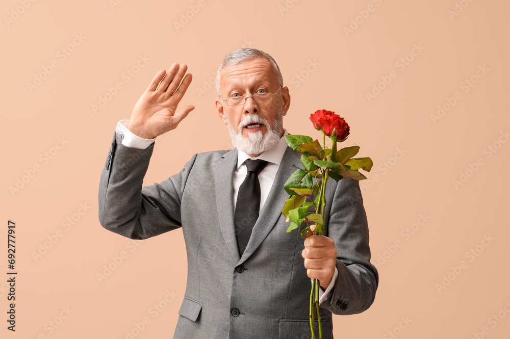 Mature man with rose flowers waving hand on beige background. Valentine's day celebration Mature man with rose flowers waving hand on beige background. Valentine's day celebration