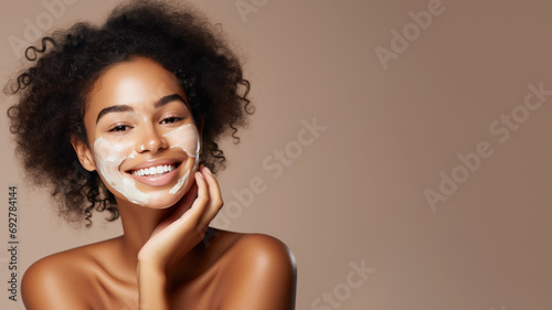 Afro woman with a healthy glowing skin is applying a skincare product.