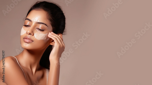 Indian woman with a healthy glowing skin apply a skincare product