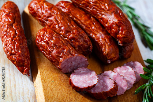 Sliced half-smoked sausages susena on wooden table. Traditional Chezh meat products