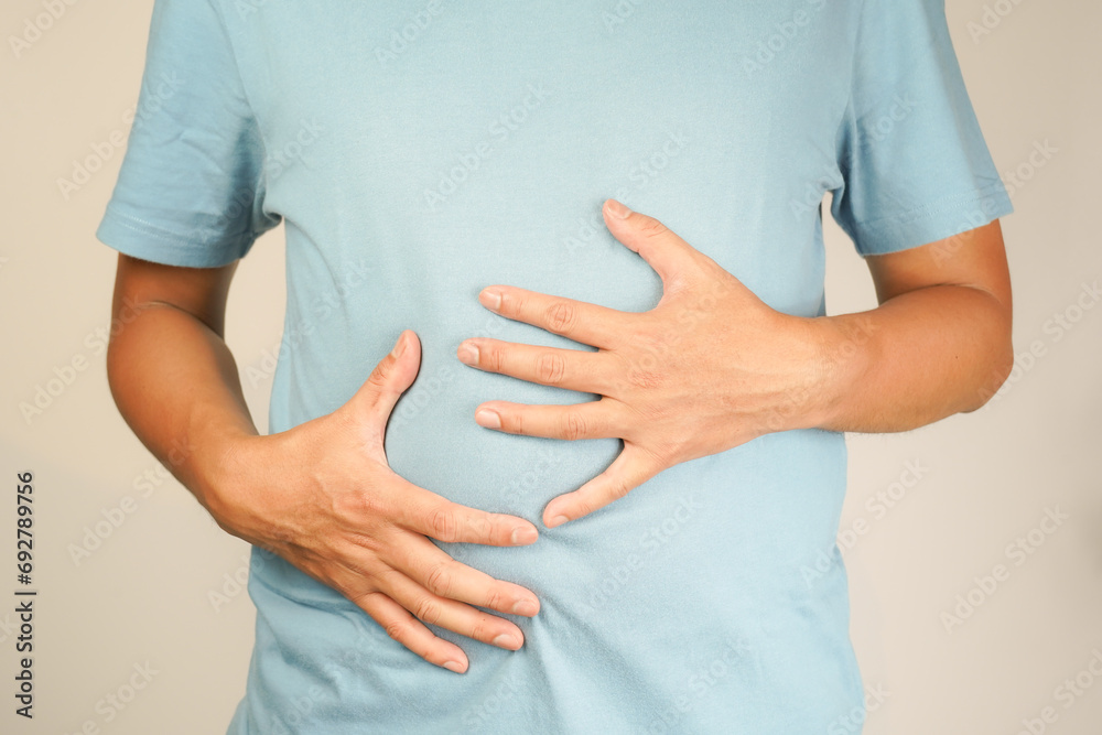 male having stomach ache, bending over and holding hands on stomach