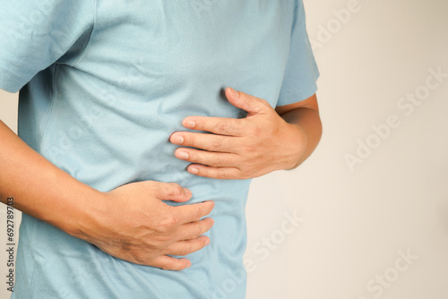 male having stomach ache, bending over and holding hands on stomach, uncomfortable due to stomach cramps, gastric pain