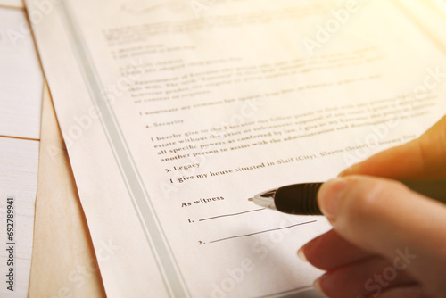 Woman signing Last Will and Testament at table, closeup photo