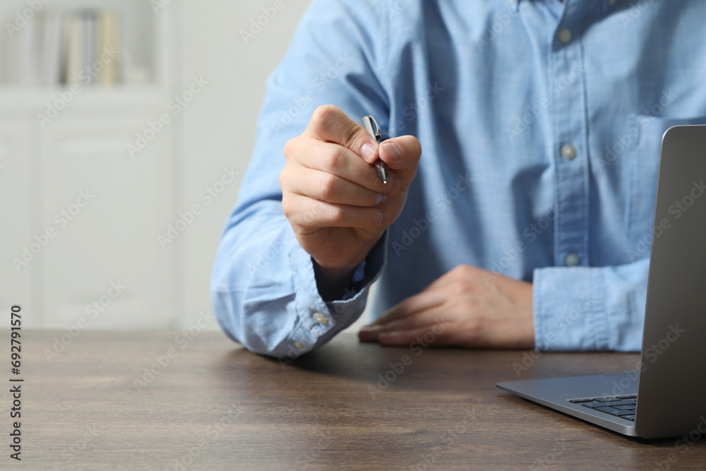 Man with pen and laptop at wooden table, closeup. Space for text Man with pen and laptop at wooden table, closeup. Space for text