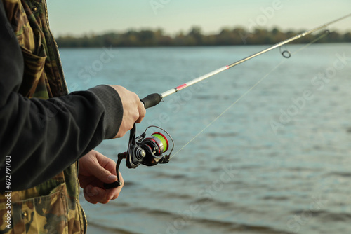 Fisherman with rod fishing at riverside, closeup. Space for text