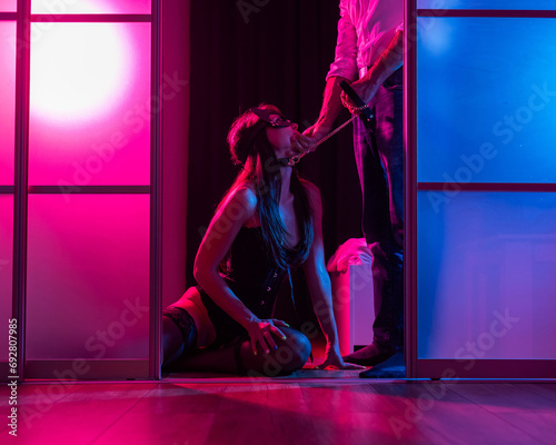 A woman is kneeling in front of a man. BDSM sex concept. Vertical photo.  photo