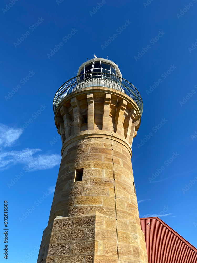 Lighthouse on the island at daytime. Sandstone lighthouse at the top of a hill. Coast ligthouse against a blue sky. Lighthouse in the harbor. Lighthouse on the coast of the region sea. Lighthouse on the island at daytime. Sandstone lighthouse at the top of a hill. Coast ligthouse against a blue sky. Lighthouse in the harbor. Lighthouse on the coast of the region sea.