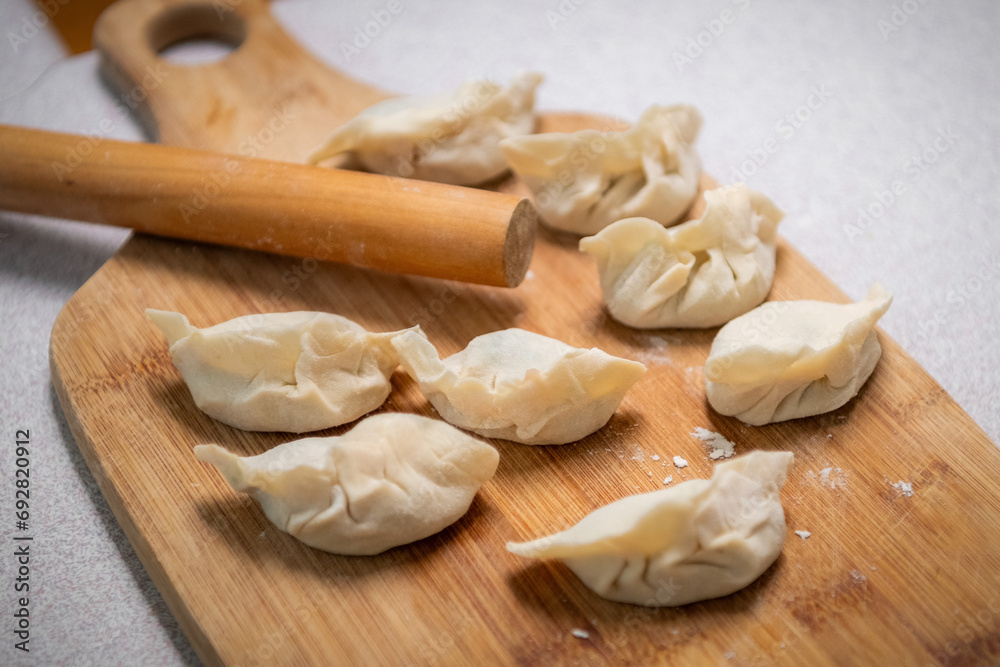 Process of making chinese dumplings. Raw dough and rolling pin on wooden chopping board. Process of making chinese dumplings. Raw dough and rolling pin on wooden chopping board.