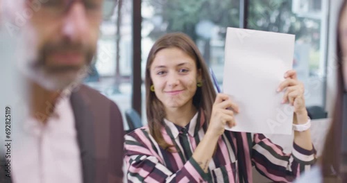 Work colleagues discussing startup project ideas. One happy girl dancing and fooling in the background. Caucasian business team at glass wall with sticky notes. Scrum with colorful stickers.
