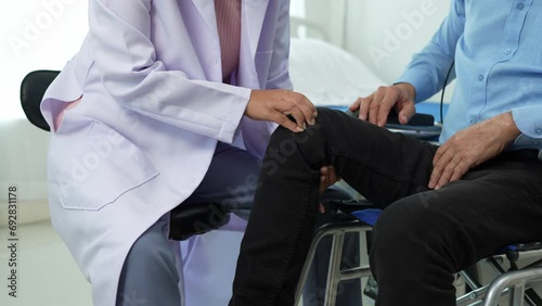 Elderly Asian male patient with severe knee pain sitting in a wheelchair undergoing treatment at the clinic, and hospital Looking for relief from a medical professional. Health insurance concept. photo