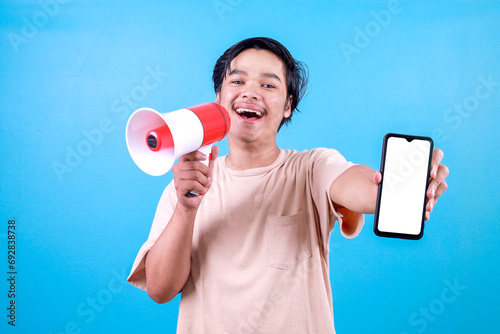 Foto Happy young man in casual t-shirt talking loudly using megaphone promoting produ