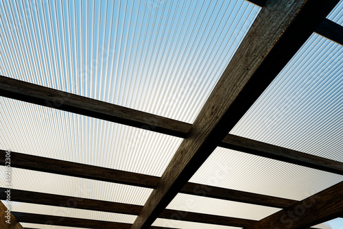 Wooden canopy roof structure made of colored polycarbonate.