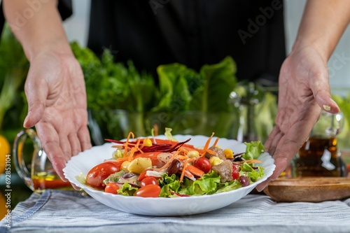woman chef show mix fresh green baby cos salad and pour salad dressing in glass blow. Organic Vegetables mix all green salad In glass bowl. Breakfast fresh salad and clean vegetable.