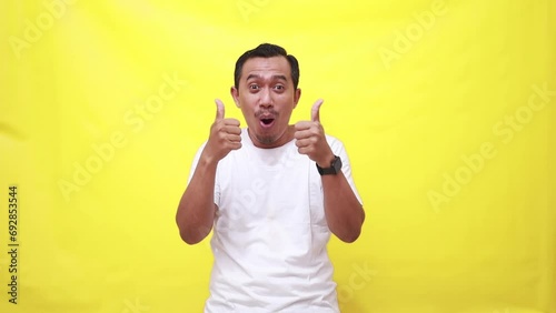 Happy man, dancing and thumbs up in success, good job or winning against a yellow studio background. Portrait of excited male person showing like emoji, yes sign or OK for positive mindset or agree photo