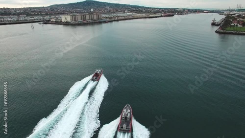 High drone footage of American coast guard boats sailing towards Los Angeles Harbor at sunset, USA