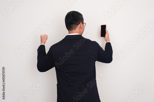 Quadro em tela Back view of businessman clenched fist showing success gesture while looking to