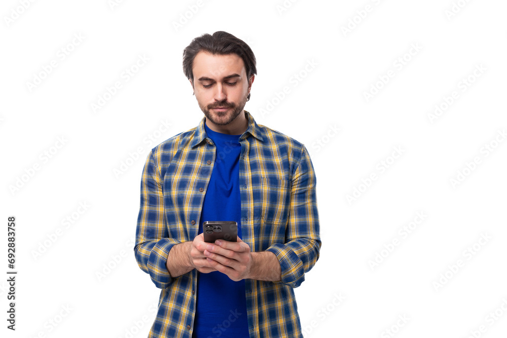 stylish well-groomed brunette brutal man with a beard in a plaid shirt reads a message on a smartphone stylish well-groomed brunette brutal man with a beard in a plaid shirt reads a message on a smartphone