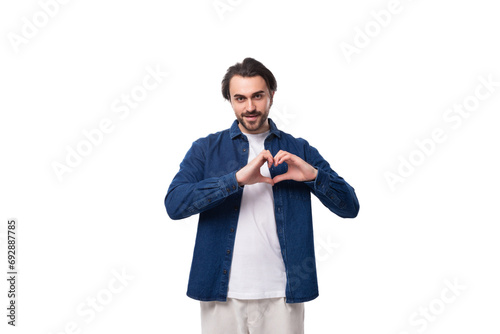 young smart caucasian man with black hair dressed in a blue shirt and t-shirt shows his heart with his hands