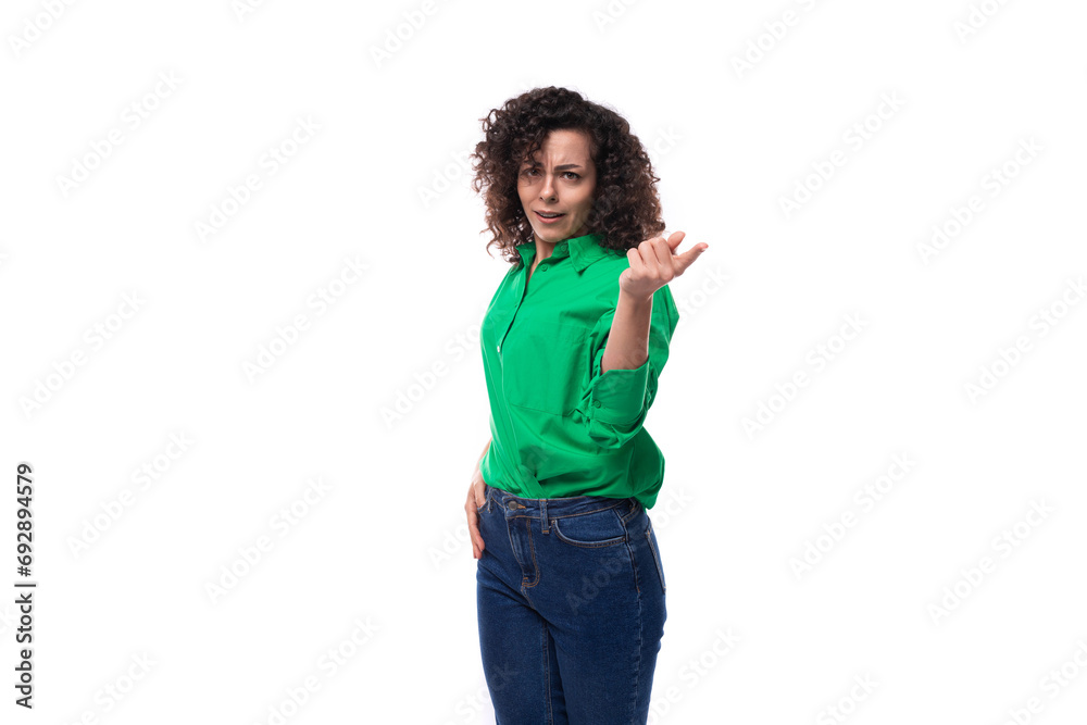 young stylish caucasian brunette woman with curled hair dressed in a green shirt posing on a white background with copy space young stylish caucasian brunette woman with curled hair dressed in a green shirt posing on a white background with copy space