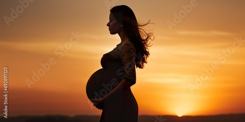 Artistic rendering of a pregnant silhouette against a sunset, highlighting the silhouette of the baby bump