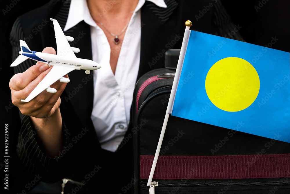 Φωτογραφία business woman holds toy plane travel bag and flag of Palau
