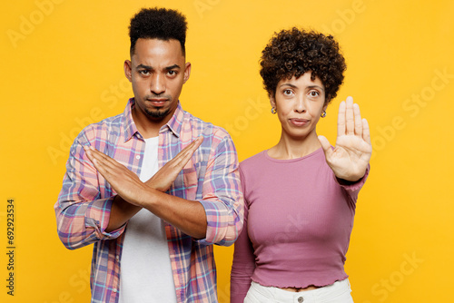 Young couple two friend family man woman of African American ethnicity wear purple casual clothes together showing stop gesture with palm hold hands crossed isolated on plain yellow orange background photo