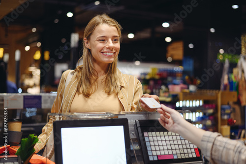 Young customer woman in casual clothes give seller credit bank card at checkout shopping at supermaket store grocery shop buy with trolley cart choose products in hypermarket Purchasing food concept photo