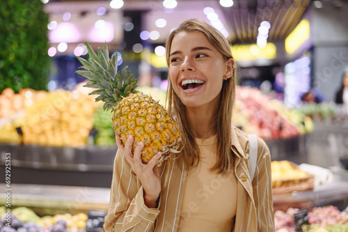 Close up young happy customer woman wear casual clothes hold pine-apple shopping at supermaket store grocery shop buying choose fruit products inside hypermarket. Purchasing food gastronomy concept.