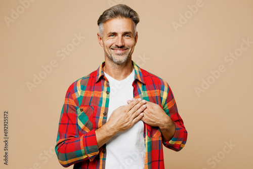 Adult smiling cheerful man wear red shirt white t-shirt casual clothes put folded hands on heart look camera isolated on plain pastel light beige color background studio portrait. Lifestyle concept. #692925572