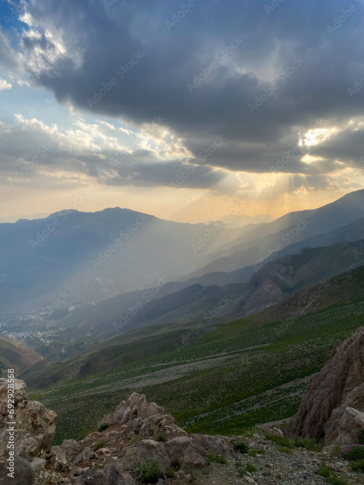 Sunset beam against the background of multi-level mountains and mountain meadows