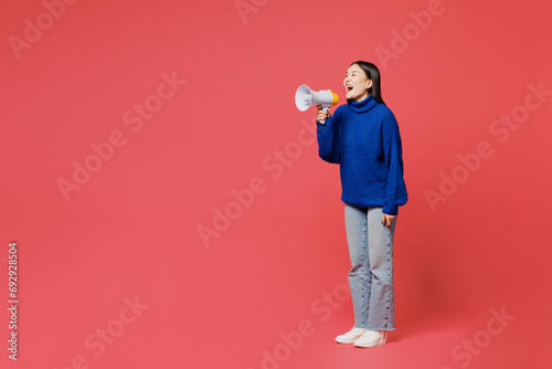 Full body young woman of Asian ethnicity she wear blue sweater casual clothes hold in hand megaphone scream announces discounts sale Hurry up isolated on plain pastel pink background studio portrait.