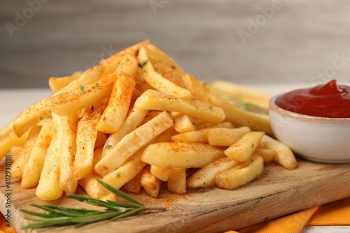 Delicious french fries served with sauce on wooden board, closeup