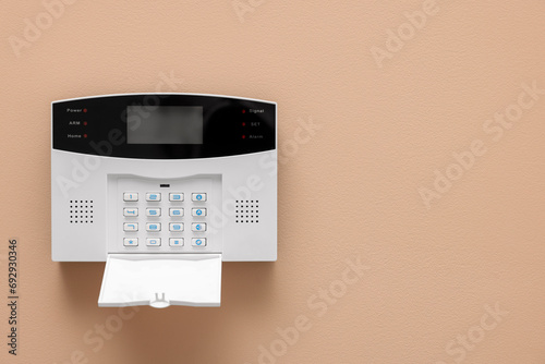 Home security alarm system on beige wall, space for text