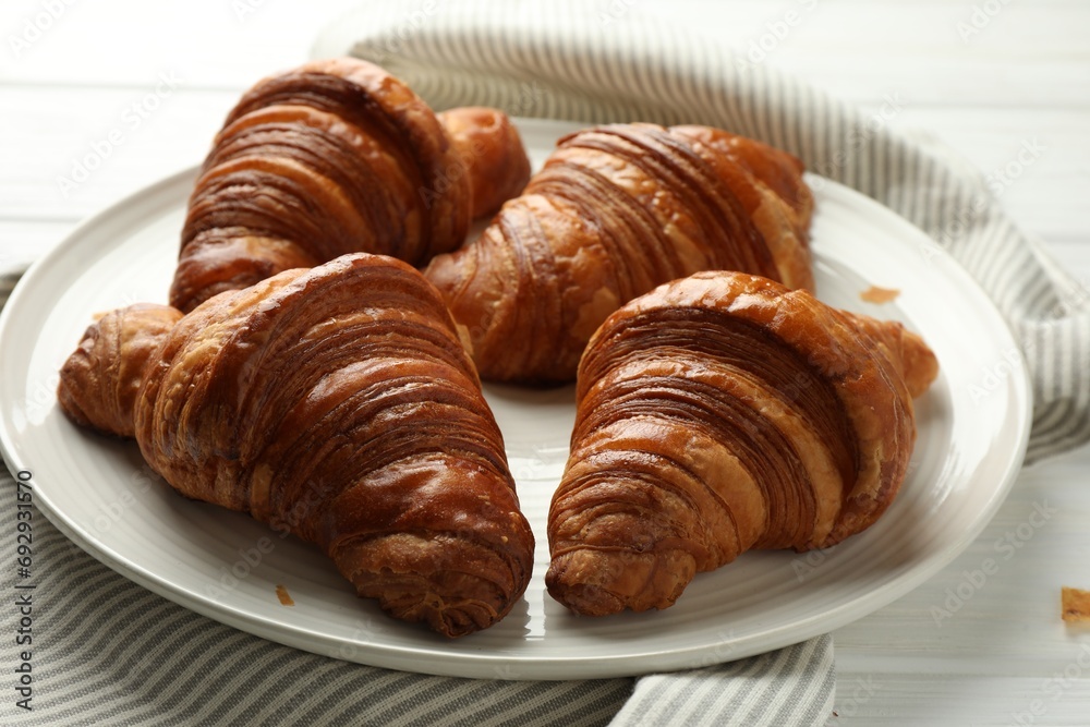 Plate with tasty croissants on white wooden table, closeup