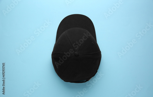 Stylish black baseball cap on light blue background, top view